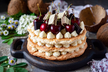 Sweet dessert: walnut cake with sweet cream, cherries and sweets for breakfast. Close-up