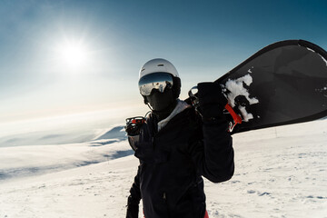 Snowboarder with board, poised against clear blue sky and pristine snow slopes, ready for the...