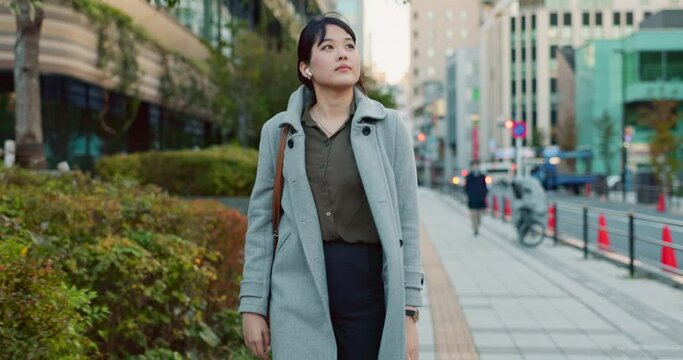 Woman, Asian and walk on sidewalk, travel or commute to work with professional in city with earphones. Listening to music on journey, podcast and commuter on urban street in Tokyo with playlist