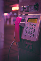 Vertical closeup shot of a public phone booth with pink handset in Duisburg, Germany