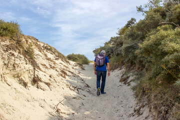 Obraz premium Man with backpack hiking in the beautiful dune in Haamstede
