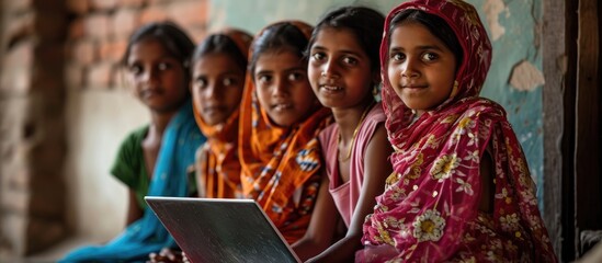 Rural girls receive online education with a laptop. - obrazy, fototapety, plakaty