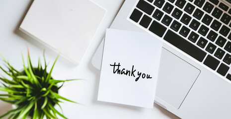 Top view of  thank you concept on the sticky note paper. Office composition with Thank You written on post it, stick to laptop.

