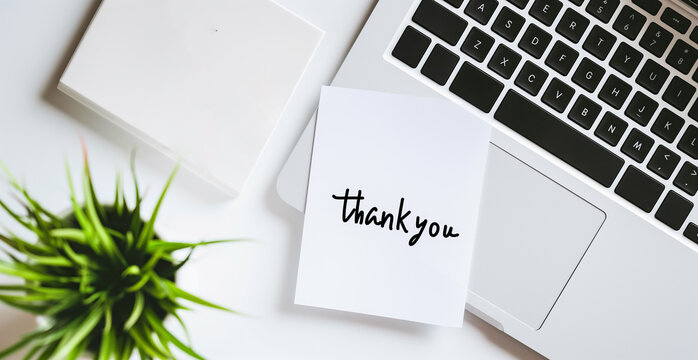 Top view of  thank you concept on the sticky note paper. Office composition with Thank You written on post it, stick to laptop.

