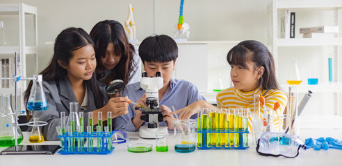 Group of school children using microscopes to study science at school