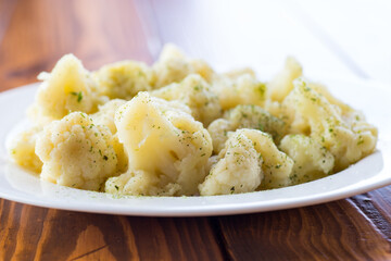 Cooked cauliflower, steamed, in a plate with spices .