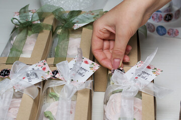 A woman packs homemade marshmallows in gift boxes. Bending with tape. Fasten branded tags. Zephyh...