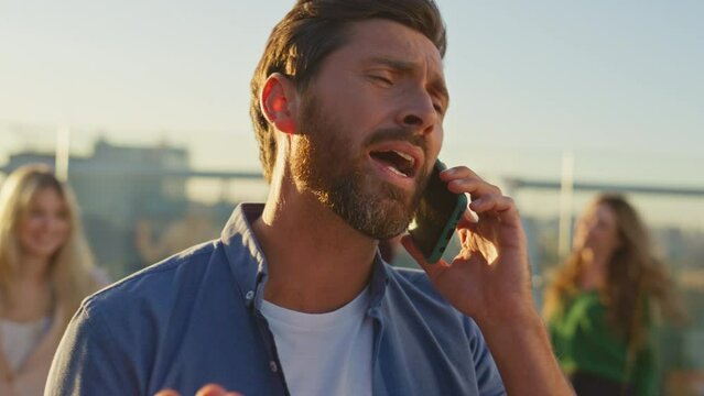 Hipster talking smartphone rooftop at friends gathering closeup. Man complaining