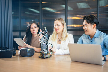 Young people sitting at a desk wearing trying out a robotic arm project. Group of multiethnic students studying together in the classroom.