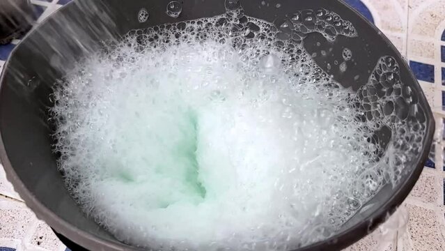 bucket with foam close-up, a man pours water into the bucket so that there is foam for washing. High quality FullHD footage