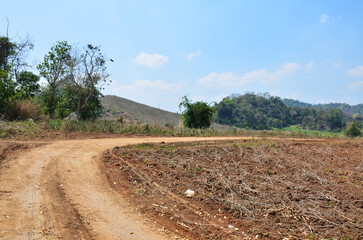 Fototapeta na wymiar Non asphalt Lateritic road or laterite rouge soils red earth street on Khao Thewada Mountain for vehicle off-road journey to Ban Taphoen Khi village at Phu Toei National Park in Suphan Buri, Thailand