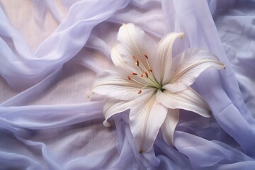  a white flower sitting on top of a bed covered in a blue sheet with a white center piece on top of it.