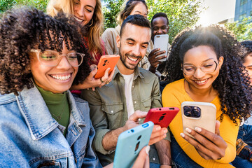 Group of young people using smart mobile phone outdoors - Happy friends with smartphone laughing together watching funny video on social media platform - Tech and modern life style concept - Powered by Adobe