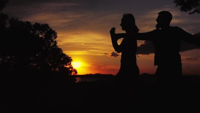 Silhouette, sunset and couple dancing in nature, love and happiness for romance, vacation or relationship. Sky, man or woman together, romanceHigh quality FullHD footage