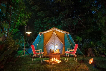 Fotobehang vintage cabin tent,  Antique oil lamp, retro chairs, Group of camping tents with outdoor coffee-making facilities on wooden tables in a forest camping area in the forest. © Pongvit