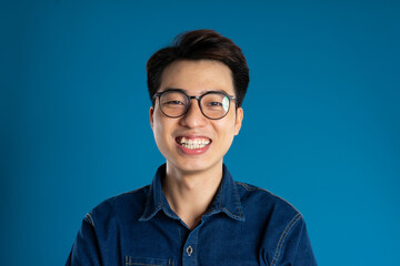 Portrait of young Asian business man posing on blue background - Powered by Adobe