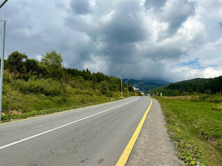 Asphalt highway road in the Carpathian mountains with heavy clouds above.