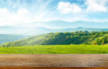 Wooden table top on blur mountain and grass field.Fresh and Relax concept.For montage product...