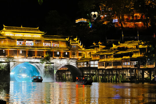 A riverboat cruises past the ancient city at night.
