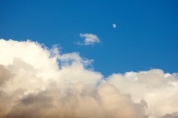 moon in the blue sky with fluffy white clouds