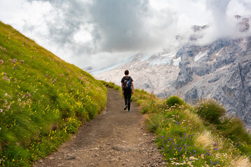 Hiker walking on trail in Dolomite alps, mountain in summer