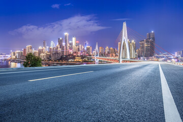 Empty asphalt road and city buildings skyline at night in Chongqing