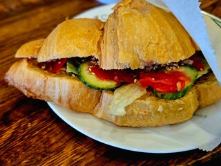 Croissant with salmon, soft cheese and salad for breakfast. Croissant with vegetables, chicken, ginger and sesame on a plate. Croissant sandwich, food closeup