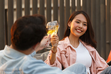 asian lover couple man and woman cheering and toast with white wine glasses to celebrating first dating in dinner party in the summertime. love, celebration, relationship and romantic concept.