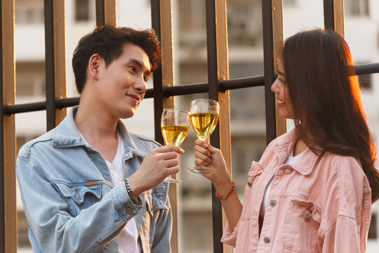 asian lover couple man and woman cheering and toast with white wine glasses to celebrating first dating in dinner party in the summertime. love, celebration, relationship and romantic concept.