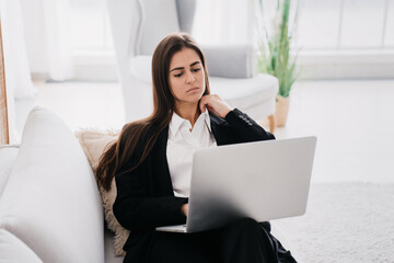 Businesswoman pondering over her laptop in a bright, modern setting