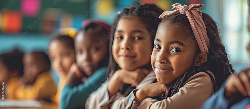 Poster Happy diverse schoolgirls sitting at desks and raising hands in classroom School study and education unaltered. with copy space image. Place for adding text or design