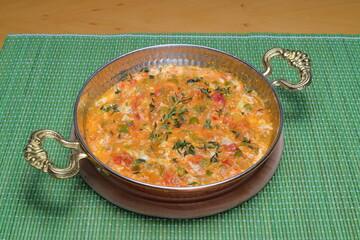 Homemade omelette with vegetables on white plate on wooden background.