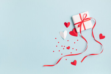 Valentine or mother day festive composition with gift or present box and red hearts on pastel blue...