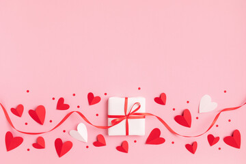 Valentine or mother day festive border with gift or present box and red hearts on pastel pink background top view. Flat lay greeting card. - 702830648