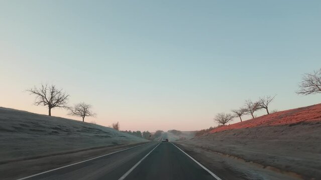View of car window and road ahead in the morning at sunrise with glowing sun
