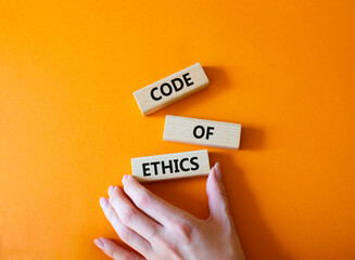 Code of ethics symbol. Concept words Code of ethics on wooden blocks. Beautiful orange background....