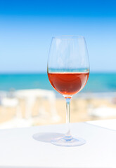 Glass of rose wine against blue water and sea