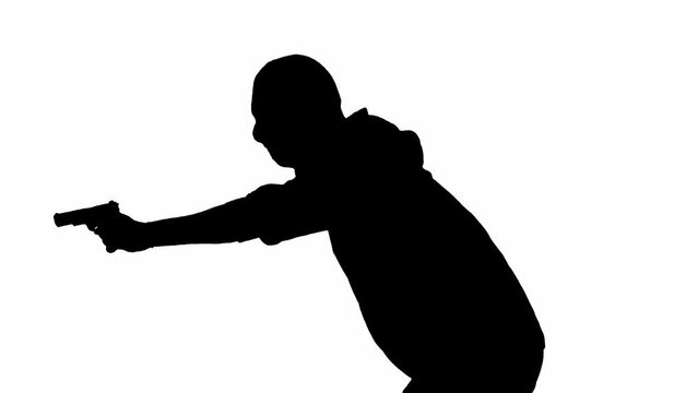 Black silhouette of thief on isolated white background. Male robber in hoodie and balaclava walking with a gun in his hands, preparing to commit a crime. Side view.