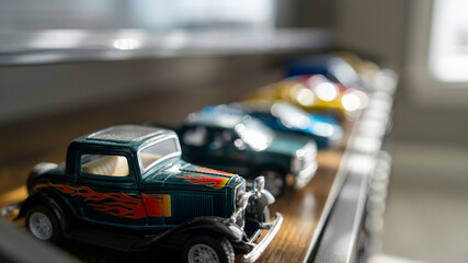 Row of colorful toy cars on a windowsill, showcasing diverse models and reflecting daylight.