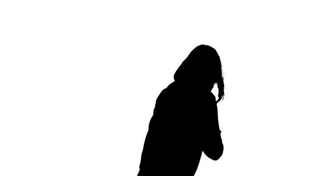 Black silhouette of a woman on a white isolated background. A young girl walks with a bat in her hands, looking around fearfully. View from the side.