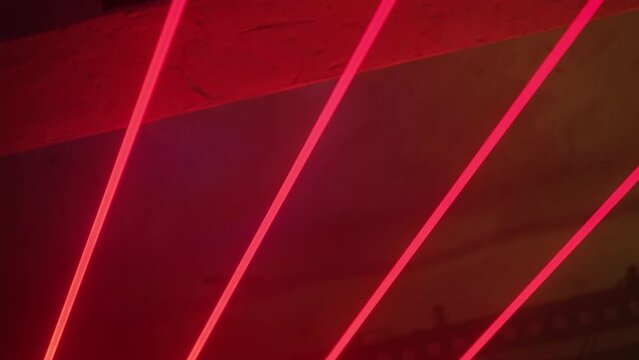 Concert spotlights in a night club glow with red laser beams.