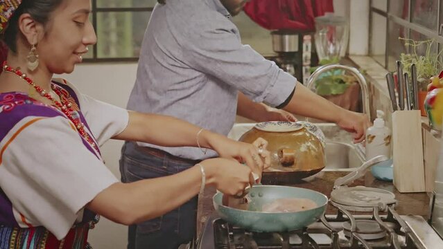 Housewife carefully places chicken pieces in the pan.