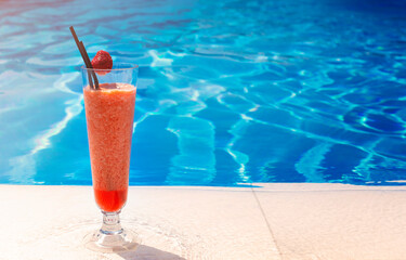 Glass with a bright red cocktail on the table by the pool with copy space
