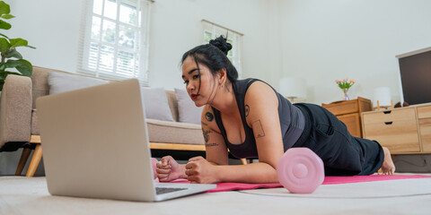 Asian overweight woman doing stretching exercise at home on fitness , online fitness class. Stretching training workout on yoga mat at home for good health and body shape