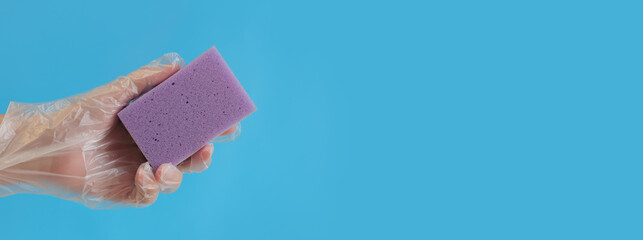 Hand and sponge for washing dishes. A hand in a glove with a sponge for wet cleaning on a blue background, a banner with a place for text