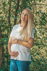Happy pregnant blonde smiling woman in the park