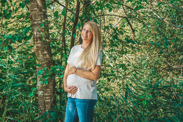 Happy pregnant blonde smiling woman in the park