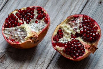 Two halves of a pomegranate on wooden rustic table. 