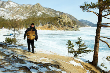 Fototapeta premium A man is a traveler behind the transparent ice floe of the frozen Lake Baikal. Winter trip. 