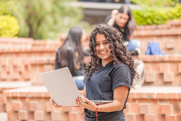 Portrait of Latin student with a personal computer in her hands.